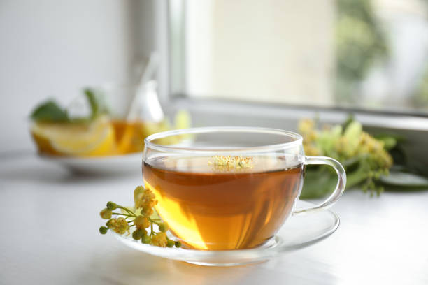 istock Cup of tea with linden blossom on white windowsill 1349349407