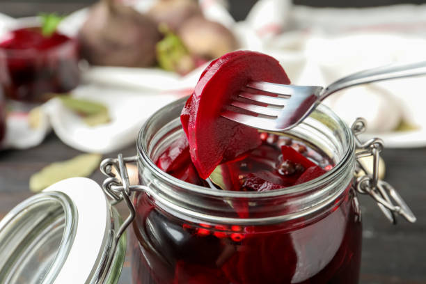 istock Fork with pickled beets over glass jar on wooden table, closeup 1349349807