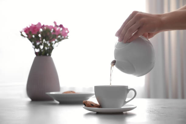 istock Woman pouring hot tea into cup at table, closeup 1349350592