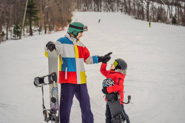 instrutor de snowboard ensina um garoto a fazer snowboard. atividades para crianças no inverno. esporte de inverno infantil. estilo de vida - 3281 - fotografias e filmes do acervo