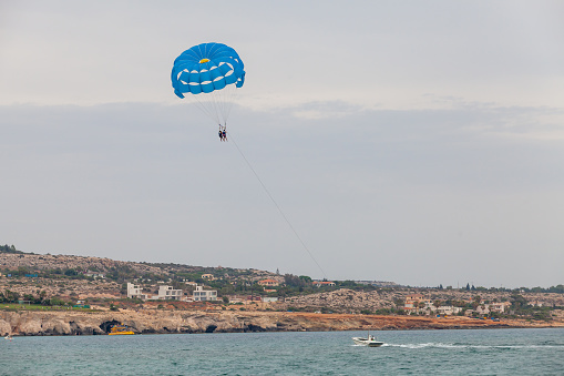 Parasailing in Agia Napa resort town, motor boat and blue parachute with tourists