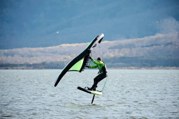 An experienced athlete rides a wingfoil in autumn on the lake