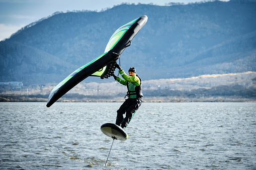 An experienced athlete rides a wingfoil in autumn on the lake