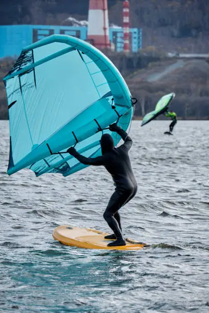 An athlete on a wingfoil board with a wing preparing for the start