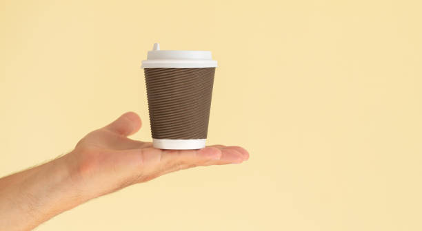 istock Man hand holding paper coffee cup with white plastic cap 1349356020