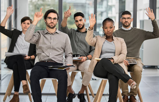 aufnahme einer gruppe von geschäftsleuten, die während einer konferenz in einem modernen büro die hand heben - panel dicussion stock-fotos und bilder