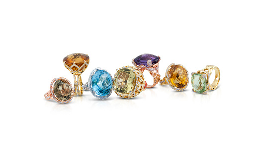 grouping of color gemstone rings with colored diamonds and gemstones on white background