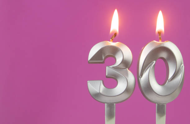 istock Silver birthday candles on pink background with room for text, number 30 1349363109