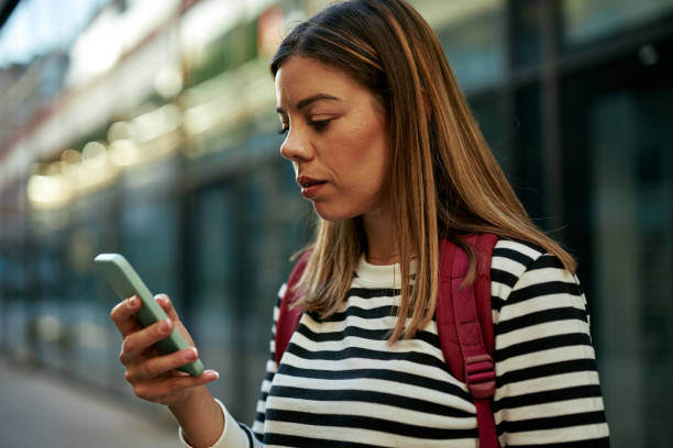 istock Young woman using smart phone on a city street 1349372242