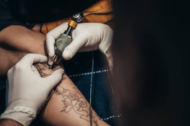 istock Tattoo artist hands in a white gloves holding a machine while creating a tatto 1349372499
