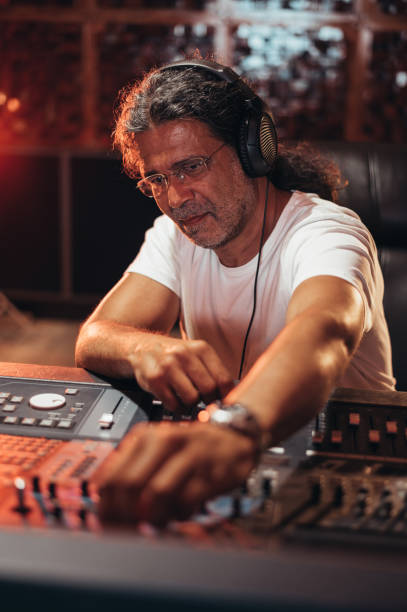 istock Senior hispanic music producer working on a mixing soundboard while in his studio 1349372535