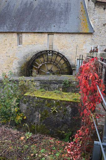 Detail of ancient watermill in Bajeux, France with autumn colors in lushious green foliage and moss