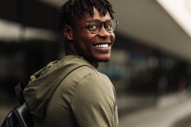 istock Happy successful african student, wearing glasses and with a black backpack, standing on the steps and smiling 1349379177
