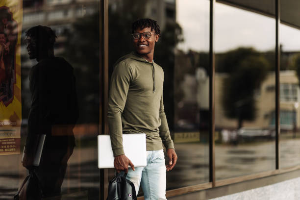 istock Happy smiling african american student with backpack and laptop on university background 1349380479