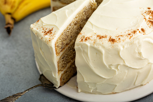 A slice of banana cinnamon layered cake with cream cheese frosting