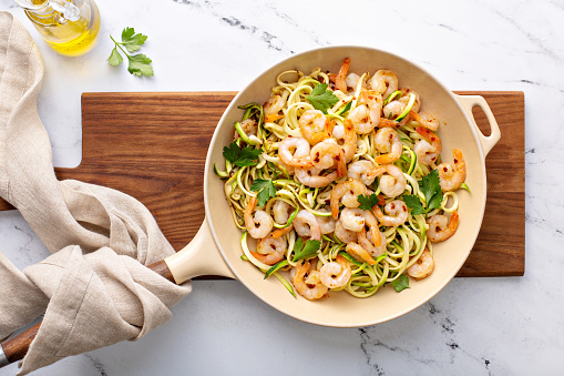 Shrimp and zucchini noodles or zoodles pasta with parmesan and chili flakes cooked in a cast iron pan