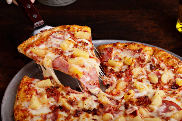Hawaiian pizza with ham and pineapple Hawaiian pizza with ham and pineapple cut into slices, cheese pull pizza stock pictures, royalty-free photos & images