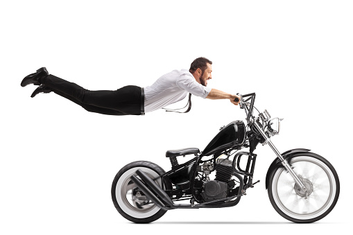 Man holding onto a chopper motorbike and flying isolated on white background