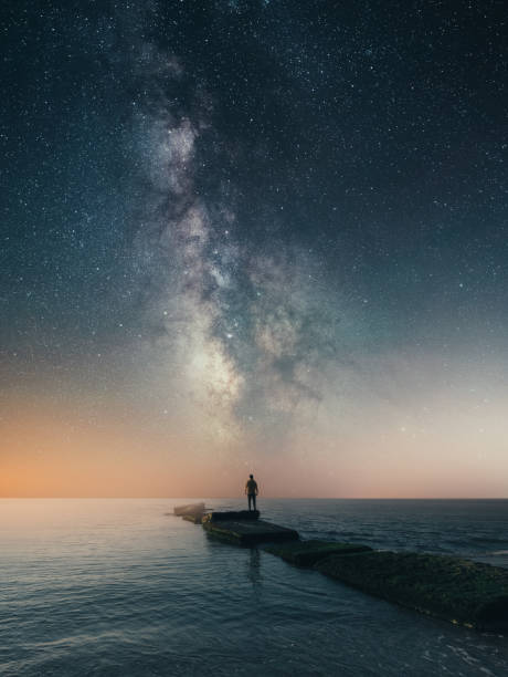 天の川の風景の下に立つ男 - sky sea night tranquil scene ストックフォトと画像