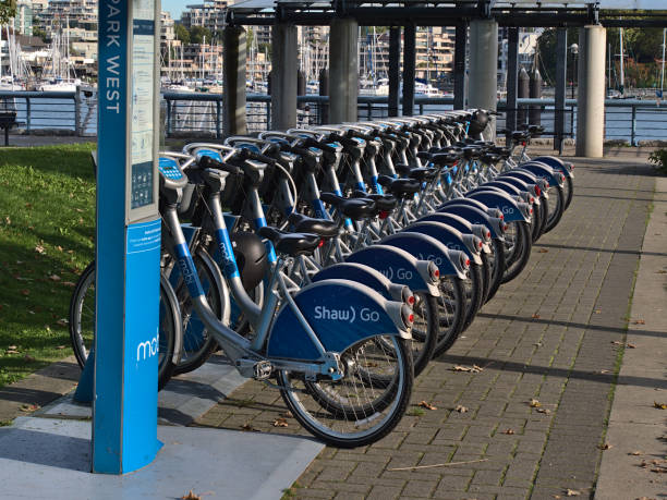 View bicycles in a row at Mobi bike share station in West David Lam Park, False Creek, operated by Vancouver Bike Share Inc. with Shaw Go advert. stock photo