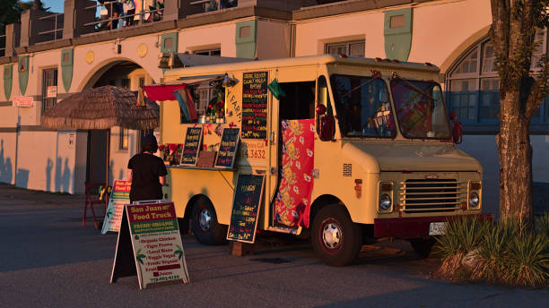 View of San Juan Food Truck selling Bolivan organic meals to pedestrians at English Bay Beach in West End, Vancouver downtown in the evening light. stock photo