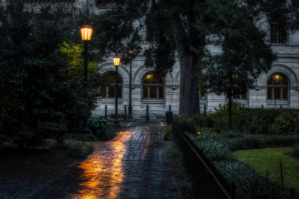 Nighttime Savannah Square Lamps reflecting off of a wet brick walkway at night in a dark square in Savannah, Georgia. savannah stock pictures, royalty-free photos & images