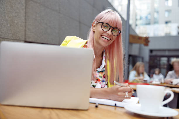 istock Optimistic woman in eyeglasses taking notes outdoors in cafe 1349388954