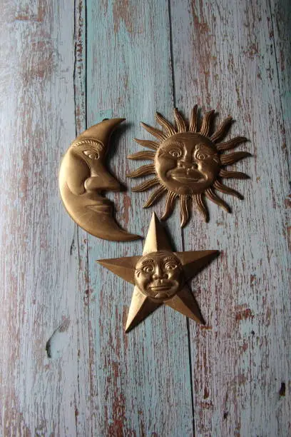 Photo of Moon, sun and star, in golden metal on an old wooden table, decoration, esoterism.