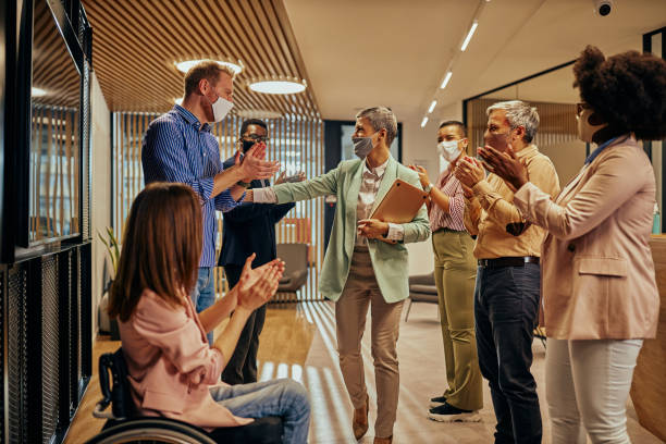 istock Coworkers greets their female colleague who return to work 1349390606