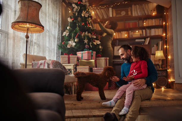 Father and daughter playing with dog during Christmastime stock photo