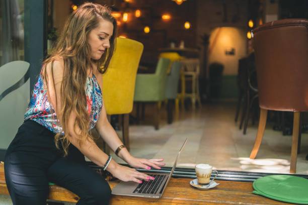 istock Businesswoman using laptop while enjoying work at cafe table with cup of coffee 1349408829