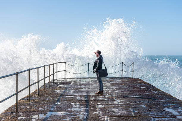 istock Business man standing on harbour wall looking out to sea. 1349410398