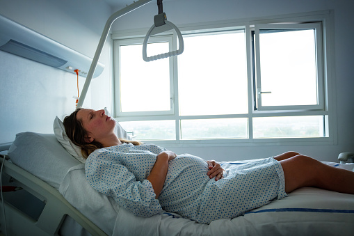 Woman in hospital bed in pain during labor in maternity ward