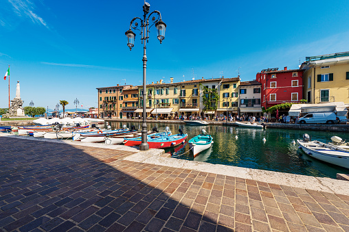 Old and small port of the Lazise village with many boats moored. Famous tourist resort on the coast of Lake Garda (Lago di Garda). Verona province, Veneto, Italy, southern Europe.