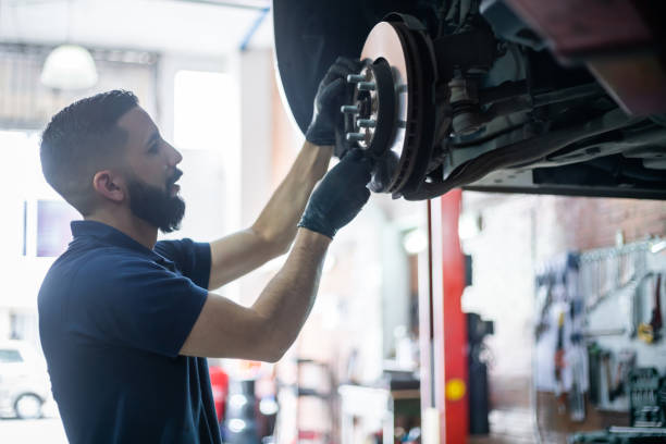 Young mechanic checking the brake disk of a car on lift at the workshop Young mechanic checking the brake disk of a car on lift at the workshop - Car industry concepts brake stock pictures, royalty-free photos & images