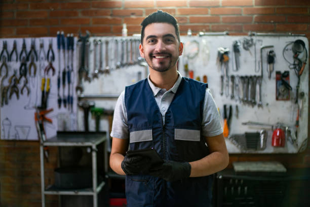 istock Friendly business owner of his garage workshop holding a tablet while facing camera very cheerfully 1349412692