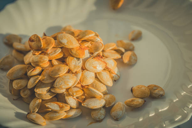 istock Fresh pumpkin seeds on a white plate. Edible vegetable seeds. 1349426089