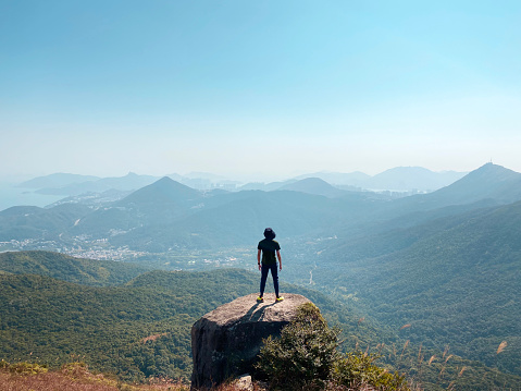 Young Asian Man Standing on Top of Rock Over Looking a Scenics Mountain View in a Sunny Day.