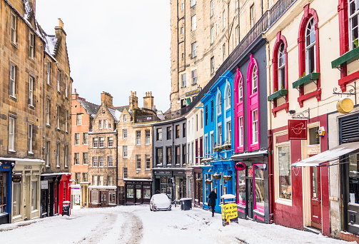 A snowy winter view looking down the historic Victoria Street, leading towards the Grassmarket in Edinburgh's historic Old Town.