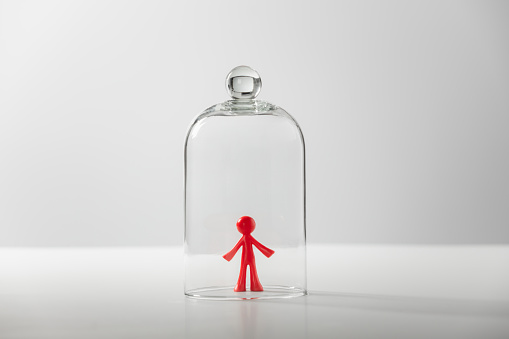Figura plástica de un hombre bajo una cubierta de vidrio: el concepto de soledad, depresión, aislamiento photo