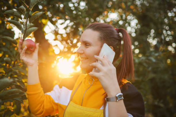 One young farmer having a call in the orchard and discussing business about organic apples