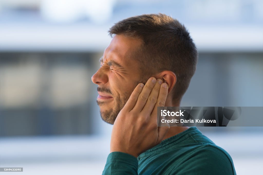 Otitis or tinnitus. Man touching his ear because of strong earache or ear pain. Otitis or tinnitus. Man touching his ear because of strong earache or ear pain. . High quality photo Tinnitus Stock Photo
