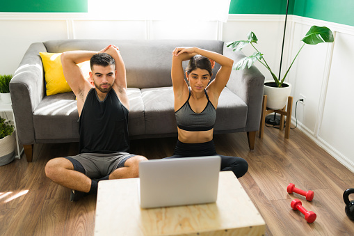 Training partners. Boyfriend and girlfriend watching a live stream and doing stretching exercises