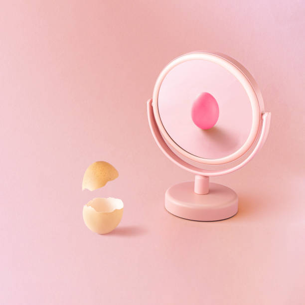 istock Egg in the mirror reflection, broken in half vs whole egg pink painted, against pastel pink background. Minimal easter concept. Creative minimal idea 1349433653