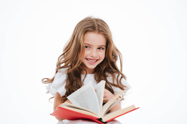 istock Cheerful little girl laughing and reading book 1349438383
