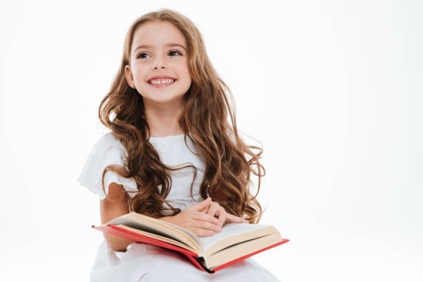 istock Smiling little girl sitting and reading book 1349438748