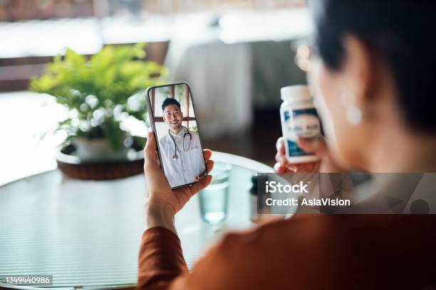 Senior Asian Woman Having A Virtual Appointment With Doctor Online Consulting Her Prescription And Choice Of Medication On Smartphone At Home Telemedicine Elderly And Healthcare Concept Stock Photo - Download Image Now