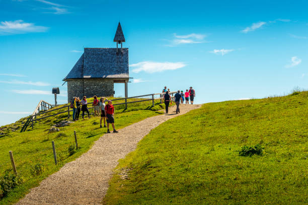 Chiemgau Alps, Germany - August 7, 2021: Hiker at a small chapel on mountain Kampenwand in the Chiemgauer Alps