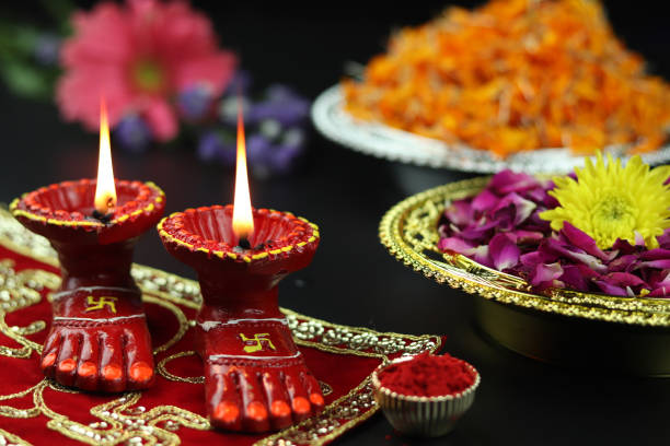 lâmpada de argila conhecida como diya, deep, diyo, deepa ou deepam with goddess feet lakshmi charan iluminando em asan de pano vermelho com flores roli sindoor e efeito bokeh. tema de shubh deepawali e laxmi pooja - diyo - fotografias e filmes do acervo