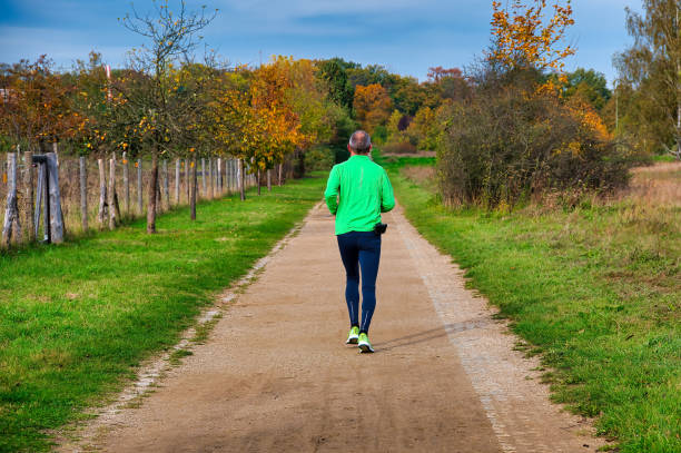 Berlin, Germany - October 25, 2021: A male jogger in sportswear from behind on a footpath in an autumnal park.